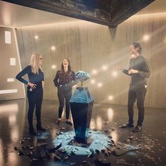 three people standing in front of a blue object