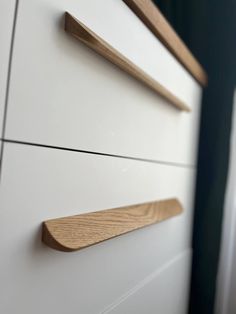 two wooden handles on white drawers in a room