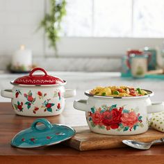 three pots with flowers painted on them sitting on a table