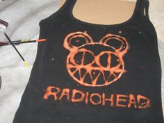 a black tank top with the word radiohead painted on it and an orange bear's head