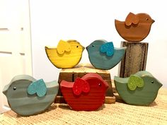 five colorful wooden birds sitting on top of a table