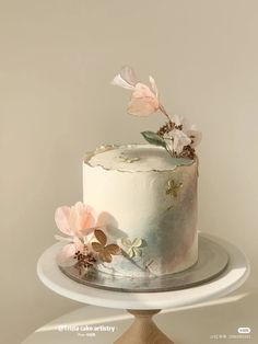 there is a white cake with flowers on the top and bottom, sitting on a plate