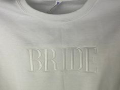 the bride t - shirt is white and has embroidered words on it that read,