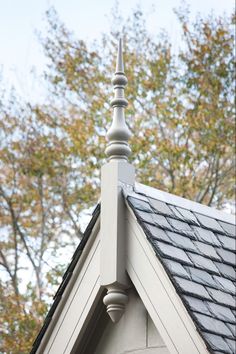 the roof of a house with a weather vane on it's side and trees in the background