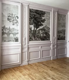 an empty room with paintings on the wall and wood flooring in front of it