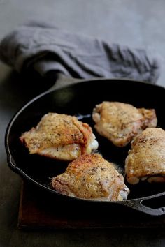 four pieces of chicken cooking in a skillet