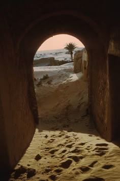 an archway leading to the beach with footprints in it