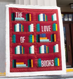 a quilted bookcase with the words love of books on it is displayed in front of a building