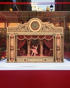 a display case with an image of a ballerina on stage in front of a red curtain