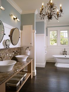 a bathroom with two sinks and a bathtub in the corner, along with a chandelier