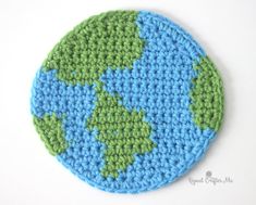 a crocheted blue and green coaster with the earth on it's surface