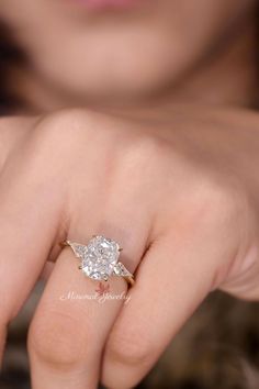 a woman's hand with a diamond ring on her finger, showing the center stone