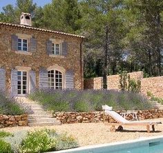 an outdoor pool with chaise lounges next to it and a stone house in the background