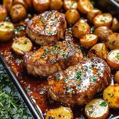 some meat and potatoes on a pan with seasoning sprinkled around them,