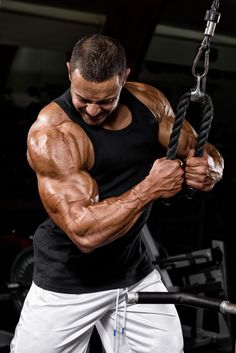 a man is holding onto a rope with his hands and shoulders, in the gym