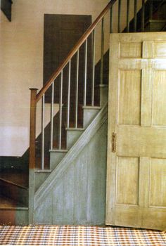 an open door is next to a set of stairs and a checkered tablecloth on the floor