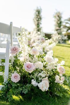 a white chair sitting on top of a lush green field next to pink and white flowers