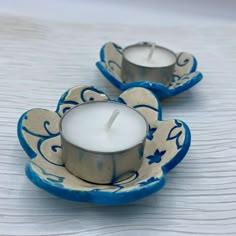 two blue and white candles sitting on top of each other in front of a plate