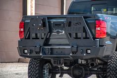 the back end of a pickup truck parked in front of a building with two large tires