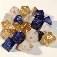 several different colored and gold dices on a white surface with numbers painted on them