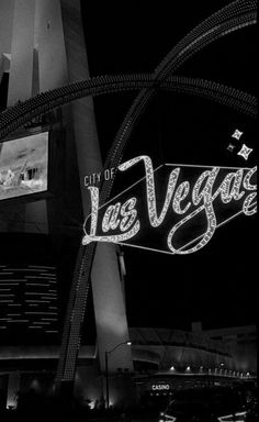 the las vegas sign is lit up in black and white at night with cars passing by