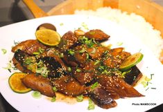 a white plate topped with meat covered in sesame seeds and garnished with green onions