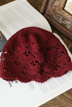 a red crocheted hat sitting on top of an open book