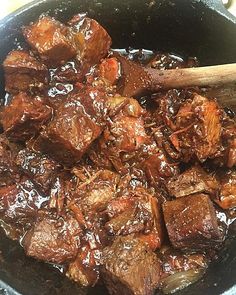 the food is being cooked in the pan on the stove top with a wooden spoon