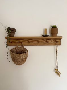 a wooden shelf with two baskets hanging from it's sides and some plants on top