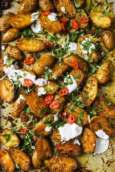 a pan filled with potatoes covered in sour cream and garnished with red peppers