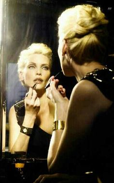 a woman is brushing her teeth in front of a mirror