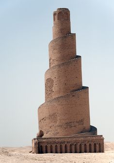 a very tall brick tower sitting in the middle of a desert area with no people around it