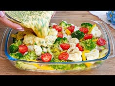 a person is dipping broccoli and cauliflower into a bowl with tomatoes