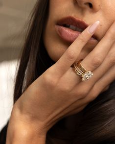 a close up of a person wearing a ring and holding their hand to her face