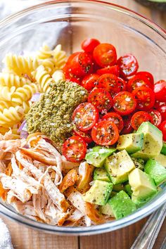 a bowl filled with pasta, tomatoes, avocado and other ingredients to make a salad