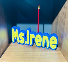 a blue and yellow word sitting on top of a wooden table next to a red pencil