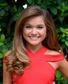 a woman in a red dress posing for a photo with her hair down and blue eyeshadow