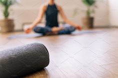 a woman sitting on the floor in front of a yoga mat