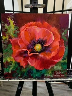 an oil painting of a red flower on a easel