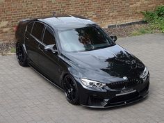 a black car parked in front of a brick wall