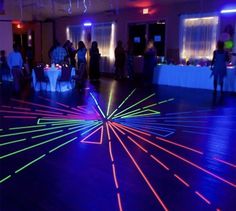 people are dancing on the dance floor with colorful lights in the room and around them