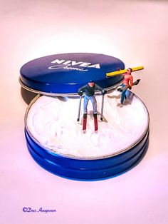 two figurines sitting on top of a blue container