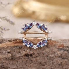 an elegant ring with blue and white stones on it, sitting on top of a rock