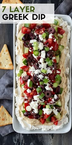 a platter filled with greek dip and pita bread, topped with olives