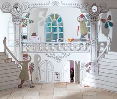 a paper cut out of a doll house with two dolls standing on the stairs and looking in