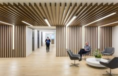 two people are walking in an office with wood slats on the walls and floor