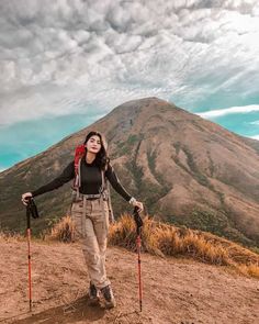 a woman standing on top of a dirt hill