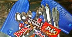 spoons, forks and candy bar wrappers are arranged in a blue holder on a table