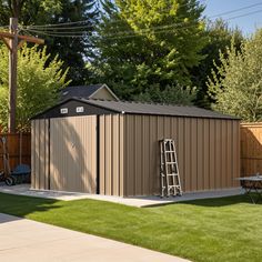 a small shed with a ladder next to it on the grass in front of a fence