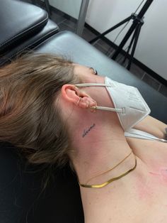 a woman laying on top of a black couch wearing an ear piece with the word love written on it